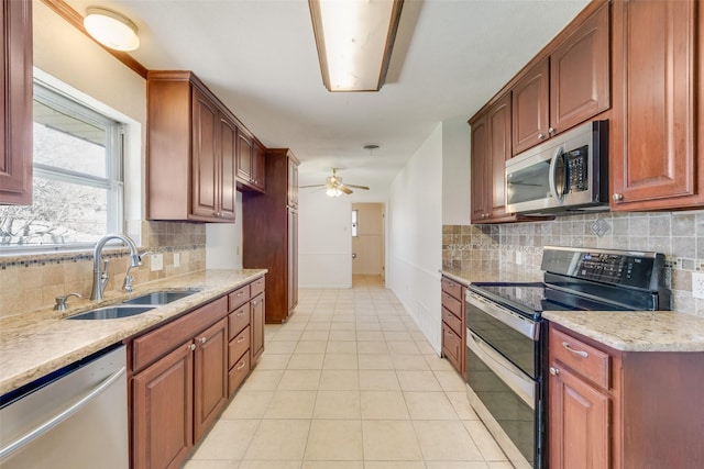 kitchen featuring light tile patterned floors, stainless steel appliances, a sink, a ceiling fan, and backsplash