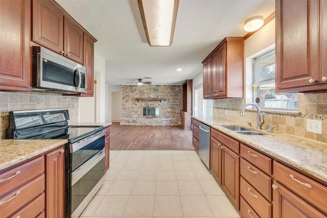 kitchen featuring ceiling fan, light tile patterned flooring, stainless steel appliances, a sink, and light stone countertops