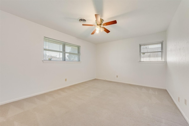 spare room with light carpet, a wealth of natural light, and visible vents