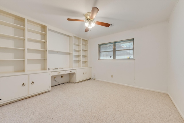 interior space featuring a ceiling fan, light carpet, baseboards, and built in study area