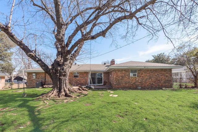 rear view of house with a yard, a chimney, fence, and brick siding