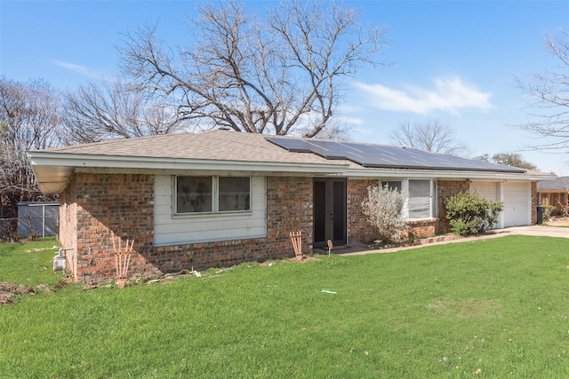 ranch-style home with a garage, a front lawn, solar panels, and brick siding