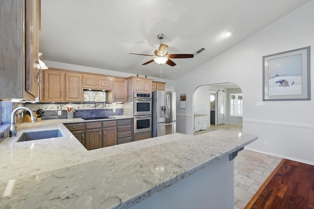 kitchen featuring a sink, stainless steel appliances, a ceiling fan, light stone counters, and lofted ceiling