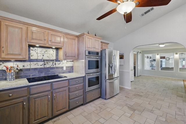 kitchen with lofted ceiling, appliances with stainless steel finishes, visible vents, arched walkways, and a ceiling fan