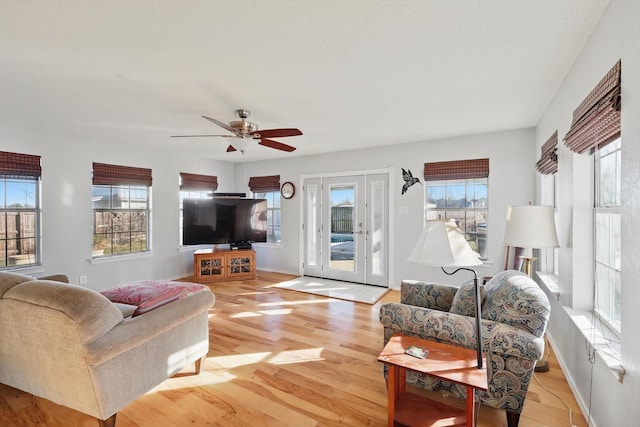 living area featuring a healthy amount of sunlight, a ceiling fan, and light wood finished floors