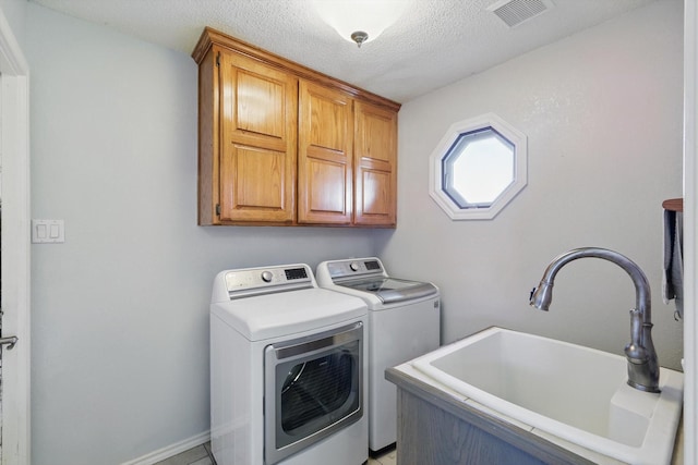 laundry area with a sink, cabinet space, washing machine and dryer, visible vents, and a textured ceiling
