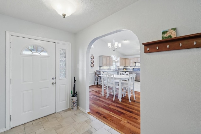 entrance foyer with an inviting chandelier, a textured ceiling, a healthy amount of sunlight, and arched walkways