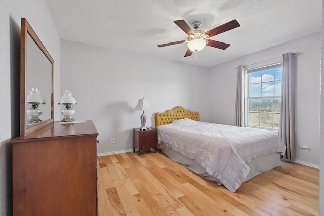 bedroom featuring a textured ceiling, light wood finished floors, and baseboards