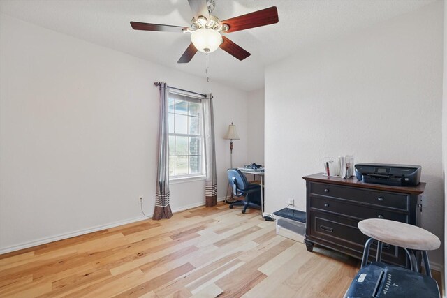 home office with light wood finished floors, a ceiling fan, and baseboards