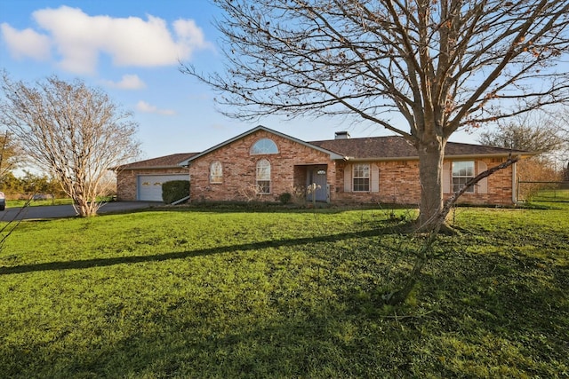 single story home featuring aphalt driveway, a chimney, an attached garage, brick siding, and a front lawn