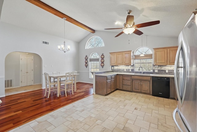 kitchen featuring a sink, visible vents, freestanding refrigerator, arched walkways, and dishwasher