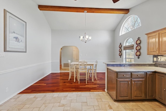 kitchen featuring arched walkways, beam ceiling, pendant lighting, a notable chandelier, and a peninsula