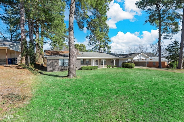 rear view of property featuring brick siding, a lawn, driveway, and an attached garage