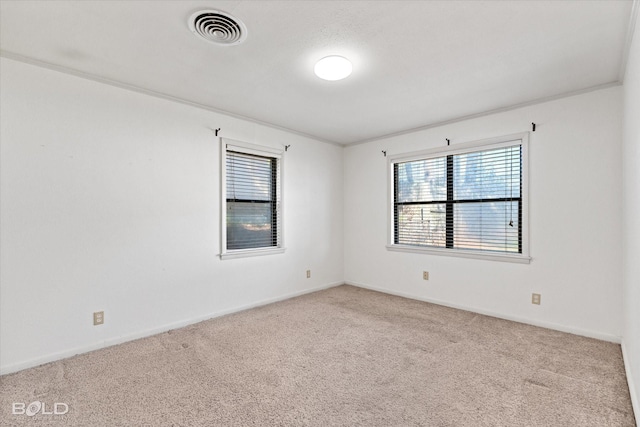 spare room featuring ornamental molding, visible vents, light carpet, and baseboards