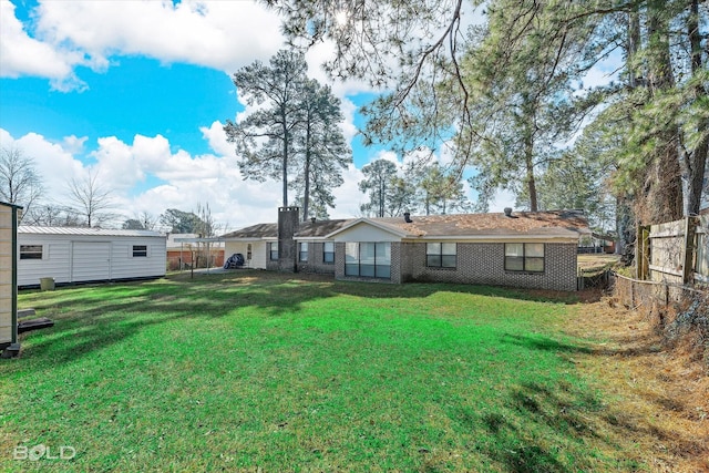 rear view of house with brick siding, a yard, and a fenced backyard