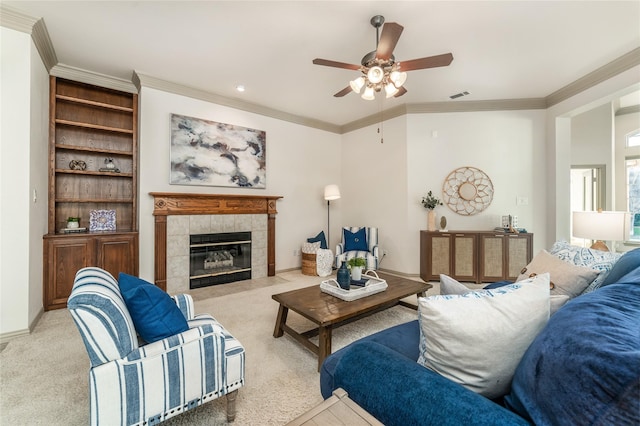 living area with baseboards, visible vents, a tiled fireplace, light colored carpet, and crown molding