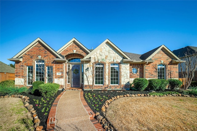 view of front of house with stone siding, brick siding, and a front yard