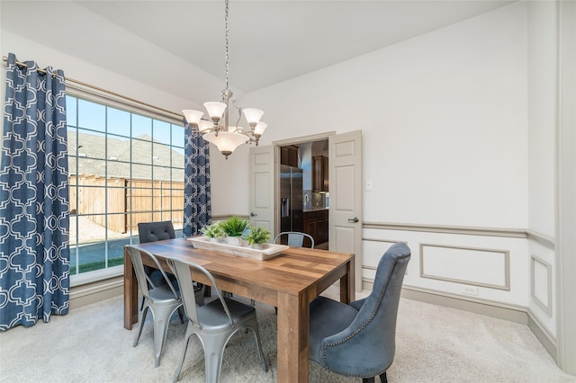 dining space featuring light carpet, an inviting chandelier, and lofted ceiling