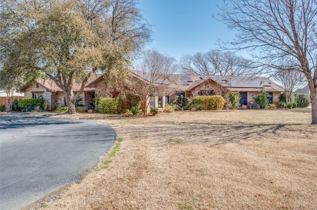 ranch-style house featuring roof mounted solar panels