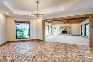 9577 Vail Eton Dr, Pilot Point, TX 76258 - unfurnished living room with a raised ceiling, healthy amount of natural light, baseboards, and a chandelier
