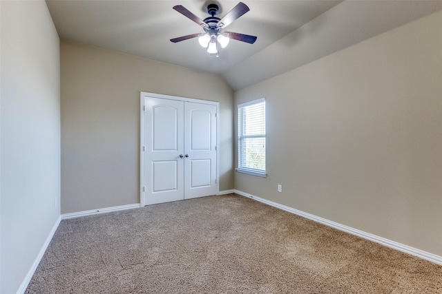 unfurnished bedroom featuring lofted ceiling, a closet, baseboards, and carpet flooring