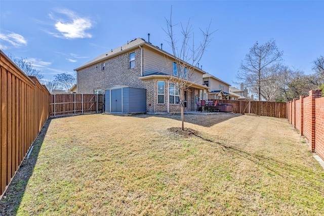 rear view of house featuring an outbuilding, brick siding, a storage unit, a lawn, and a fenced backyard