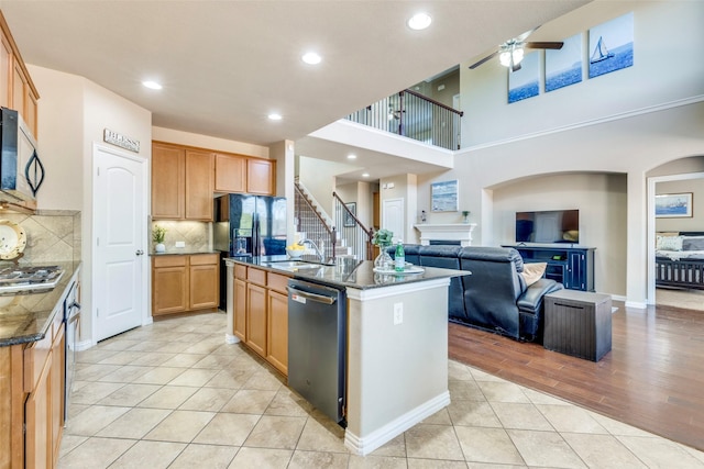 kitchen featuring a center island with sink, open floor plan, stainless steel appliances, a fireplace, and a sink