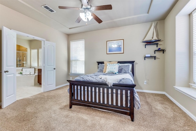 carpeted bedroom with ensuite bath, baseboards, visible vents, and ceiling fan