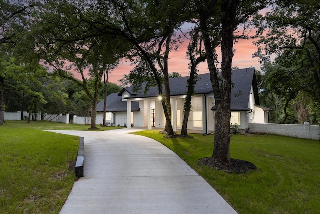 view of front of property with driveway, fence, a lawn, and roof with shingles