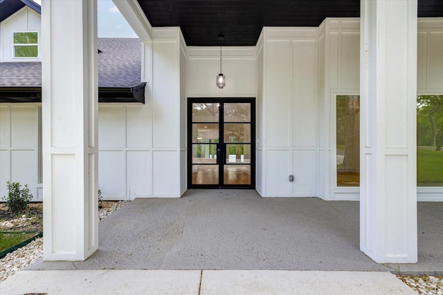 entrance to property featuring french doors and roof with shingles