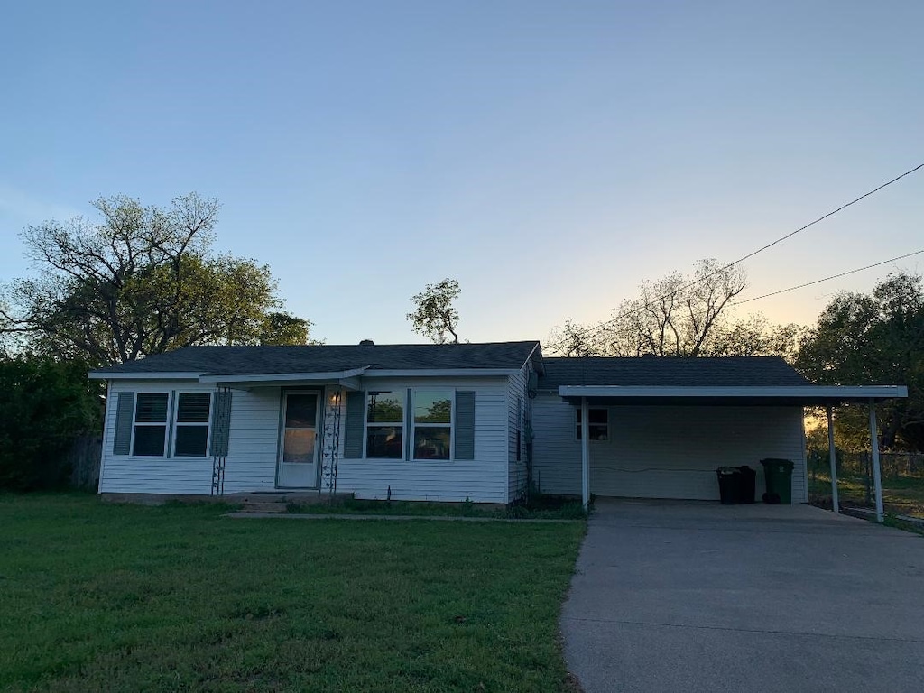 ranch-style house with an attached carport, concrete driveway, and a front yard