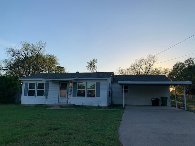 ranch-style house with an attached carport, concrete driveway, and a front yard