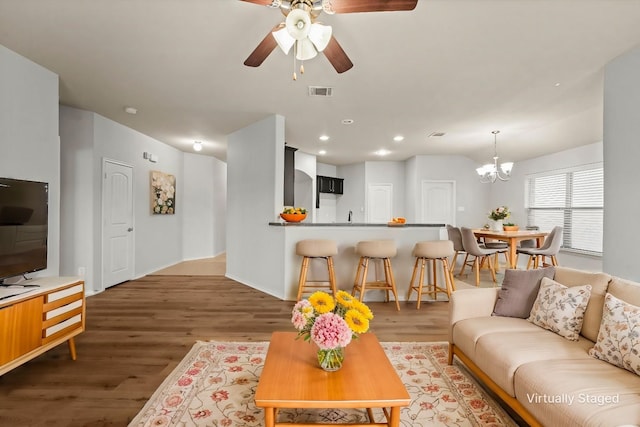 living room featuring ceiling fan with notable chandelier, wood finished floors, visible vents, and recessed lighting