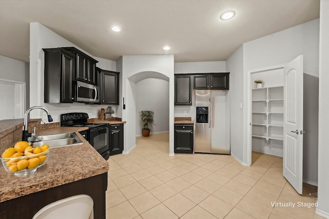 kitchen featuring light tile patterned floors, stainless steel appliances, recessed lighting, a sink, and dark cabinets