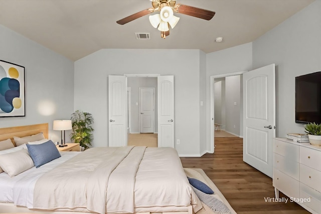 bedroom featuring light wood finished floors, visible vents, a ceiling fan, vaulted ceiling, and baseboards