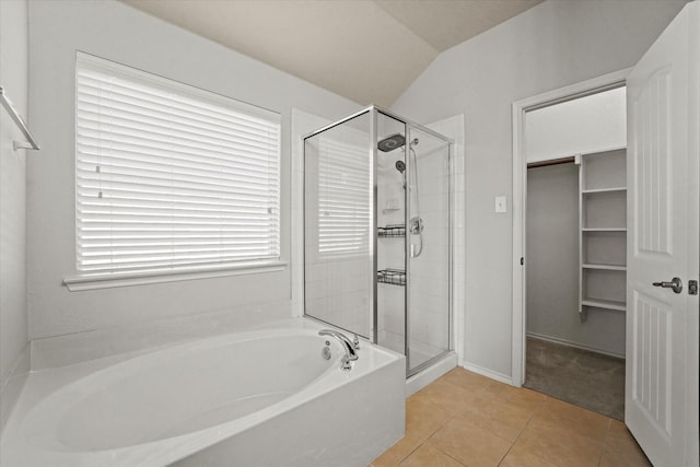 bathroom with a stall shower, a garden tub, tile patterned flooring, vaulted ceiling, and a walk in closet