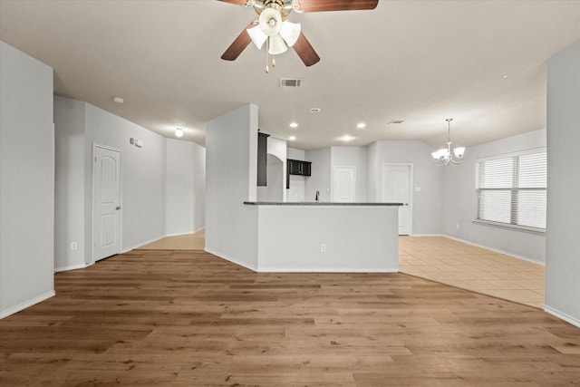 unfurnished living room featuring baseboards, visible vents, dark wood-type flooring, ceiling fan with notable chandelier, and recessed lighting