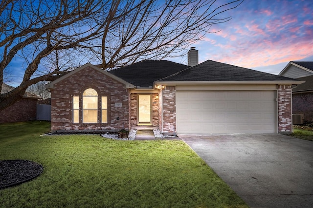 ranch-style home featuring a garage, driveway, a chimney, and a lawn