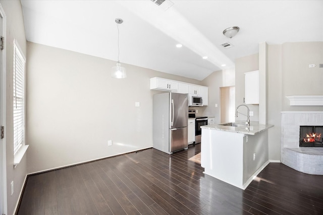 kitchen featuring a peninsula, a sink, white cabinetry, hanging light fixtures, and appliances with stainless steel finishes