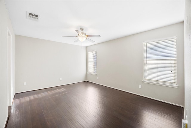 unfurnished room with baseboards, ceiling fan, visible vents, and dark wood-style flooring