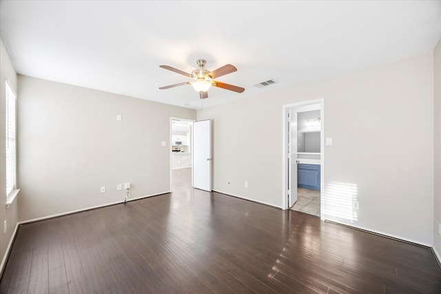 spare room featuring baseboards, ceiling fan, visible vents, and dark wood-type flooring