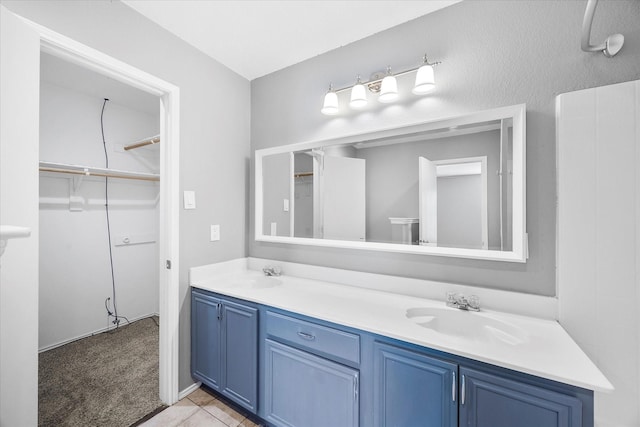 bathroom featuring tile patterned floors, a sink, a spacious closet, and double vanity