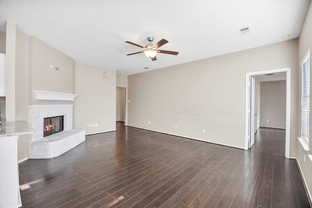 unfurnished living room with dark wood-style floors, ceiling fan, a fireplace, and visible vents