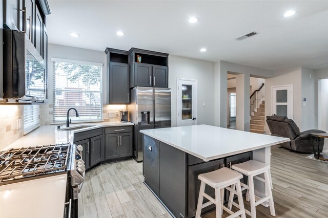 kitchen featuring appliances with stainless steel finishes, visible vents, a sink, and decorative backsplash