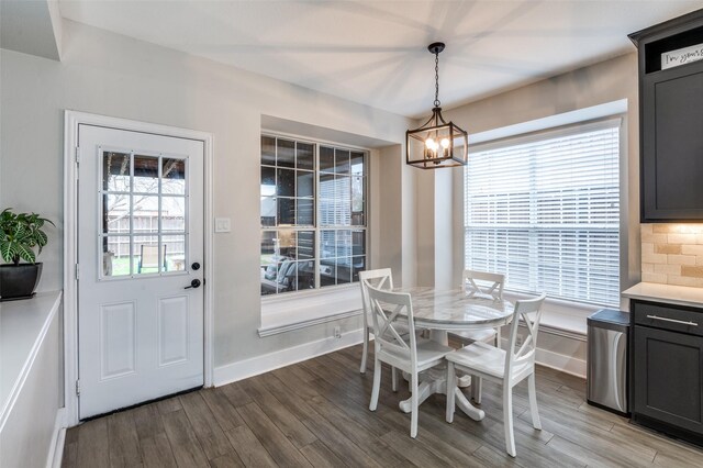 dining space featuring a chandelier, wood finished floors, and baseboards