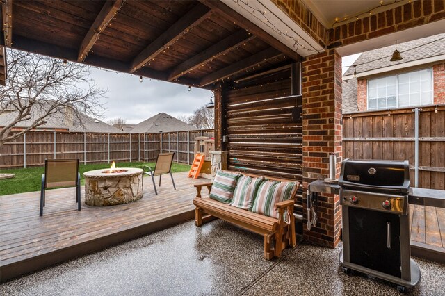 wooden terrace with an outdoor fire pit, a fenced backyard, and grilling area