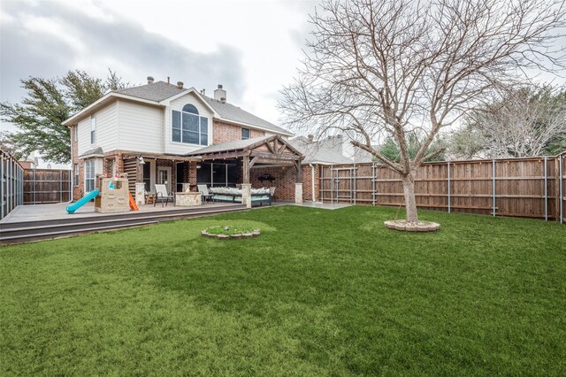 back of property featuring brick siding, a yard, a chimney, an outdoor hangout area, and a fenced backyard