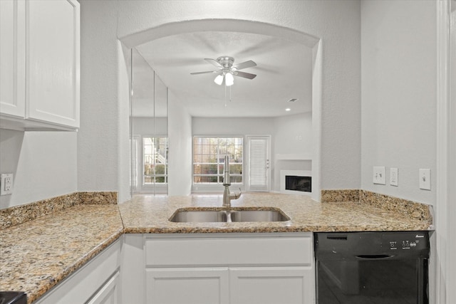 kitchen featuring light stone counters, a sink, white cabinetry, a ceiling fan, and black dishwasher