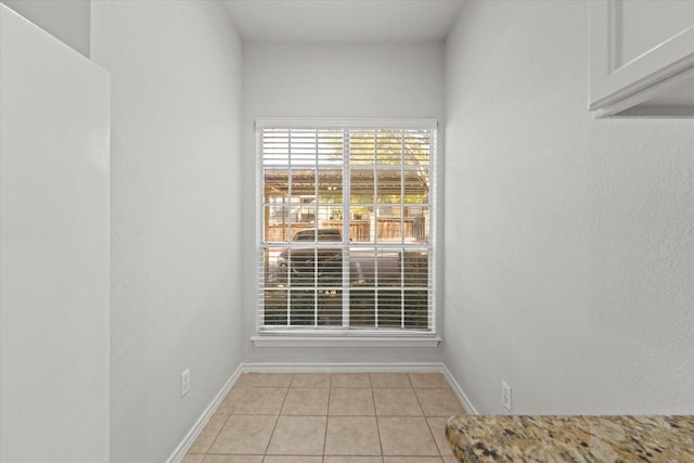 unfurnished room with light tile patterned floors and baseboards