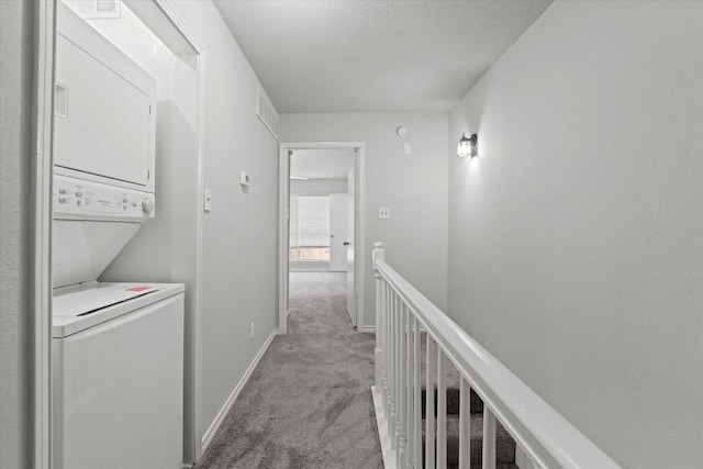 corridor featuring light carpet, stacked washer / dryer, an upstairs landing, and baseboards